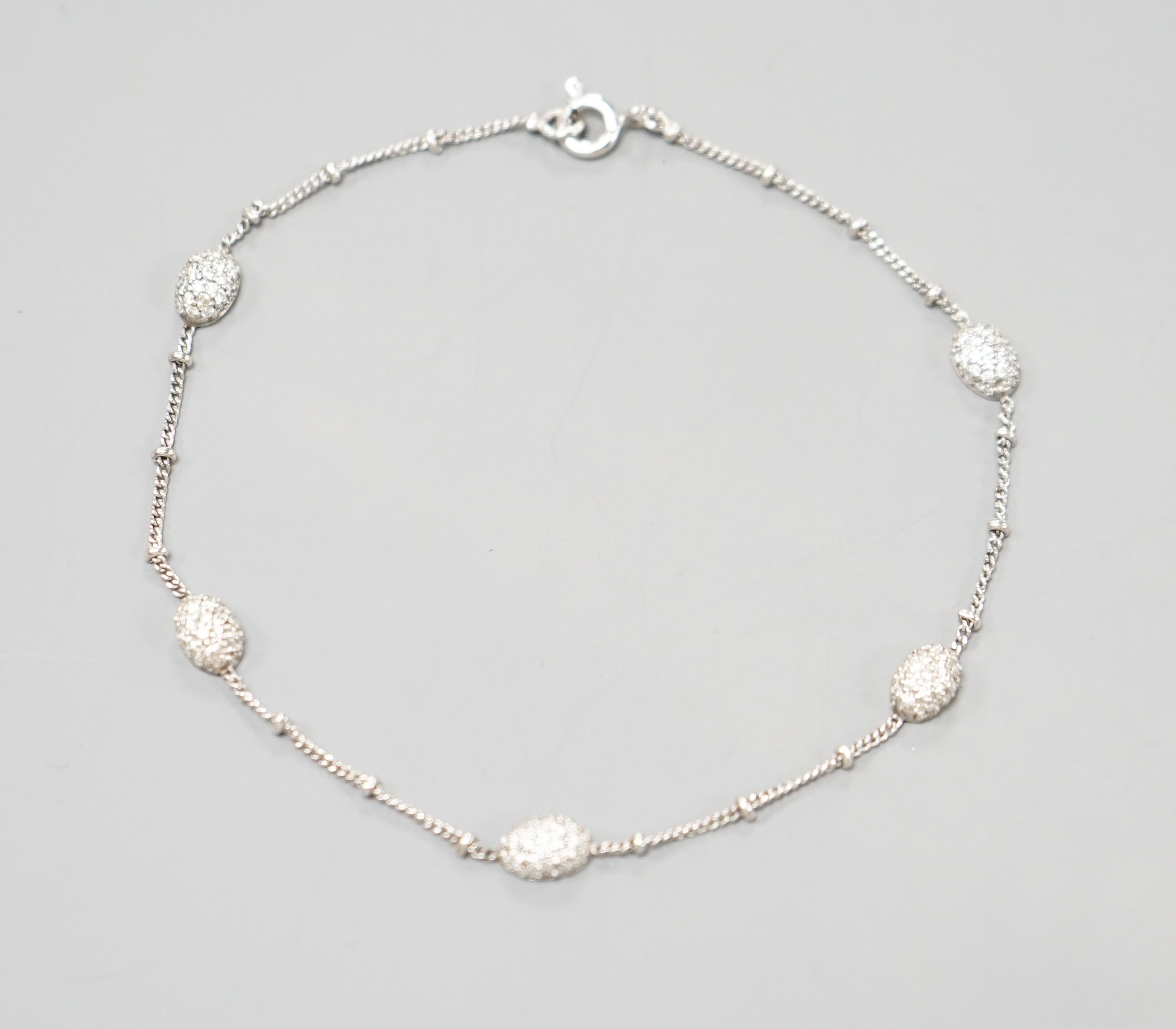 A modern 750 white metal and diamond chip set demi lune link bracelet, 19cm